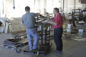 Charles Wells Jr., at left, and Charles Wells Sr. carefully assemble the frame for one of Mobile Glassblowing, LLC’s unfinished portable furnaces. 