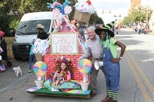 Michael Murray/Americus Times-Recorder: Kiwanis president, Jody Wade, and board member, Charlene Pennymon, stop for a photo with the first-place winner of the costume only competition, Lucy Duke, and her Candyland wagon.