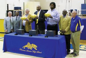 MICHAEL MURRAY I ATR: In this photo, from the Feb. 20, 2016 edition of the Tiimes-Recorder, former NFL players (holding footballs from left) Dan Reeves, Kent Hill, and Leonard Pope, are shown with members of the Sumter County School System staff after presenting the awards to the school for its role in producing three Super Bowl participants.